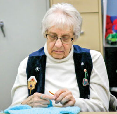  Sue Ciaglo works on knitting a child’s sweater. 