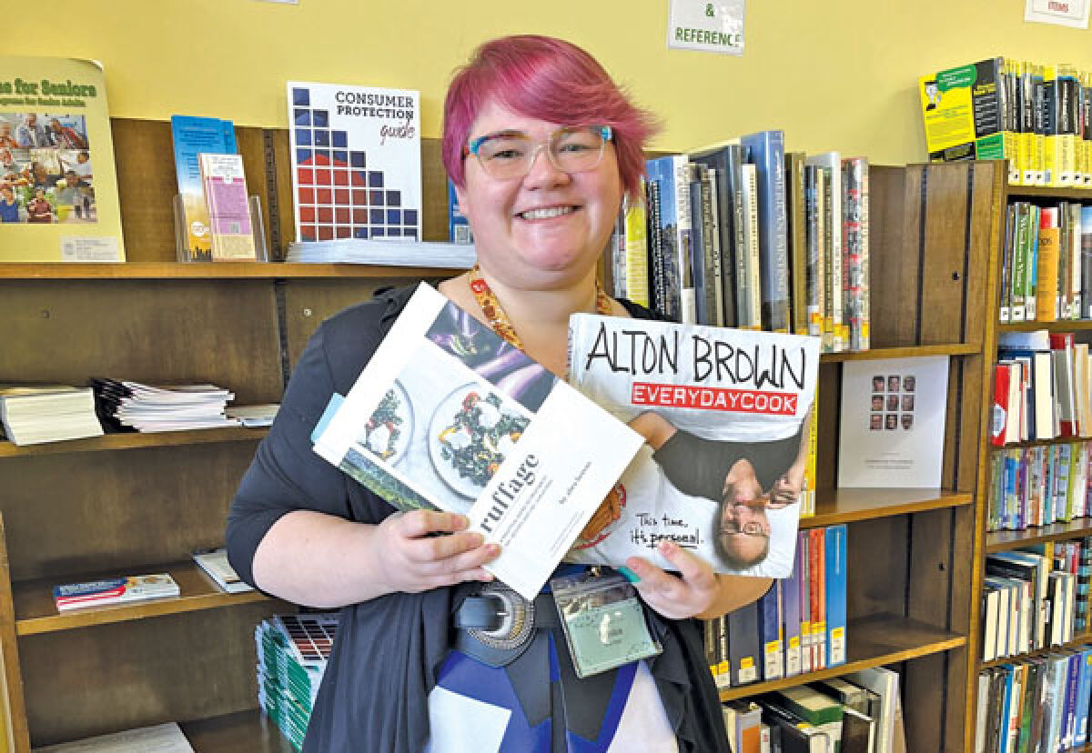  Kristen Getzin, Fraser Library’s programming and youth services librarian, shows off some of the cookbooks that will be featured in its new ‘Cookbook Club.’ 