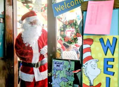  Kenny Fenchel, a retired Novi Community School District eighth grade history teacher, leaves a third grade classroom at the Academy of the Americas after making an appearance as Santa Claus and handing out gifts to the kids. 