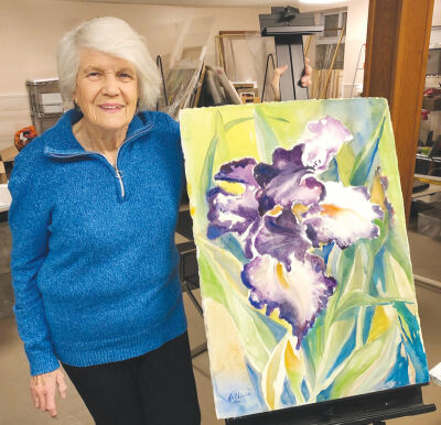  Artist Carol LaChiusa stands next to “Purple Iris,” one of her unframed artworks. 