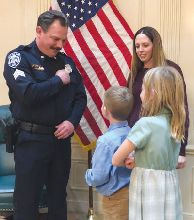  Newly minted Grosse Pointe Woods Public Safety Department Sgt. Kyle Seidel points to his sergeant badge — pinned on by his wife, Jessica Seidel — as the couple’s children, Jolene, 8, and Sawyer, 6, look on with awe 