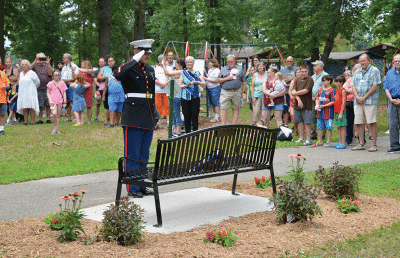  During a memorial service at Green Acres Park July 23, Marine Sgt. Keith Pouliot salutes a bench dedicated in honor of Vietnam veteran and long-time community volunteer Bobby McDermott.  