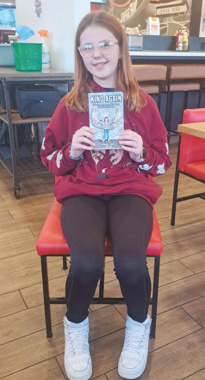  Kennadee Fabin,12, smiles as she shows off a  copy of her new book, “Kind Again: How to  return to Kindness like Dolly Parton.” 