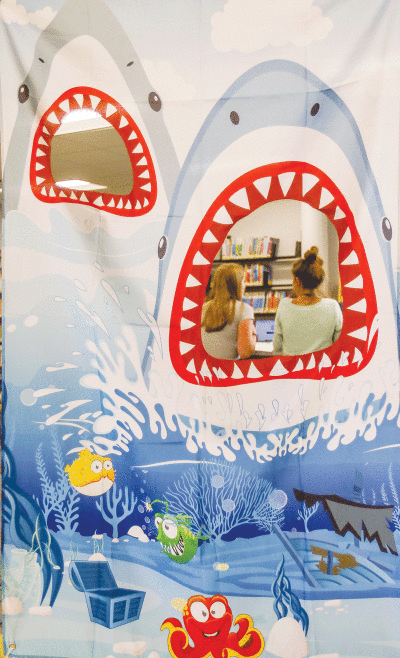  Library attendees  appear through shark mouth decorations at the library. 