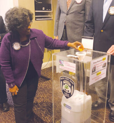  Incoming Rotary Club of Grosse Pointe Sunrise President Sandra Cobb pours pills into a new medicine safe disposal kiosk that the club purchased for Grosse Pointe Woods during the kiosk’s unveiling Jan. 25 at the Woods Community Center. The medicine safe disposal kiosk — which is now available for public use in the Grosse Pointe Woods Public Safety Department lobby — employs a bottle with an activated charcoal solution that promptly renders drugs unfit for consumption. 