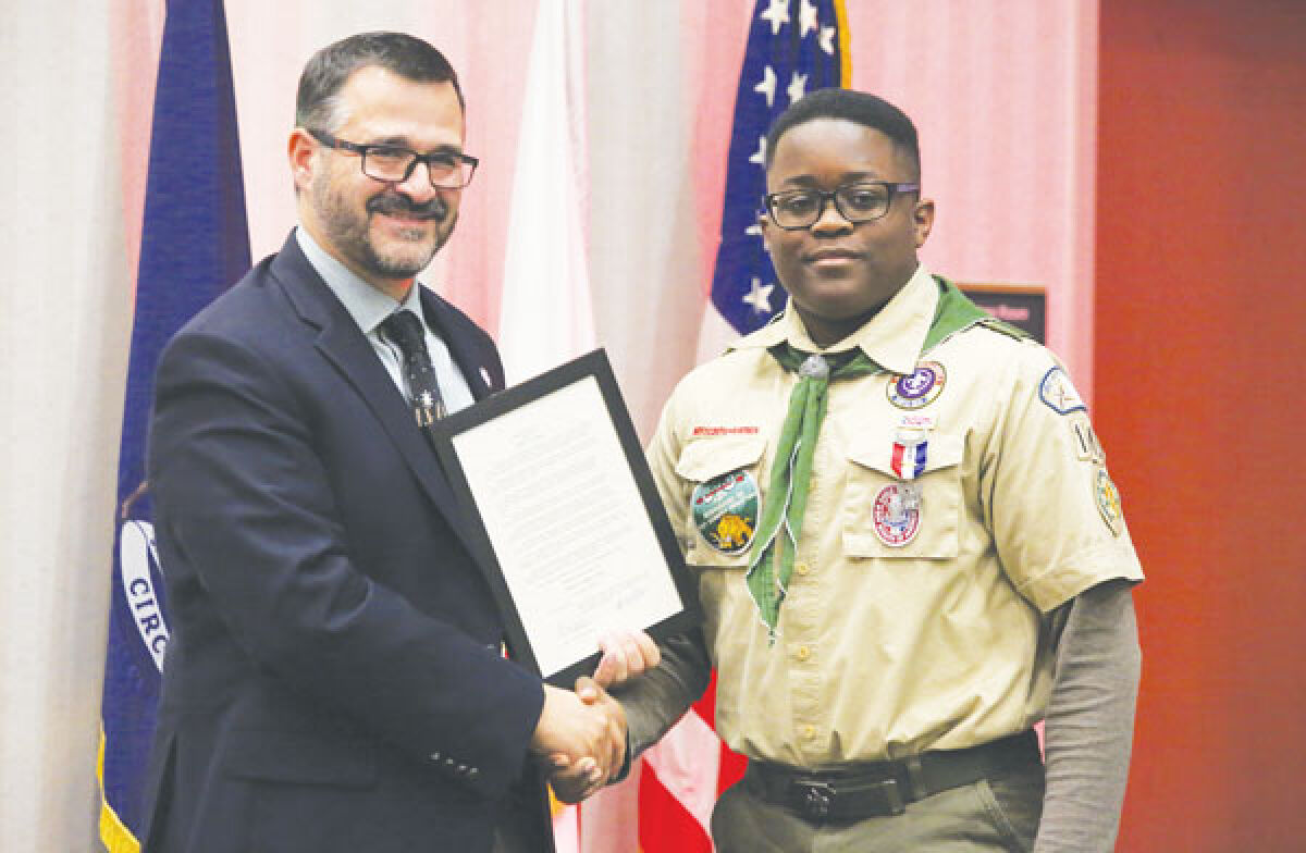  Ethan Ngwa, right, is honored by the Macomb Township Board of Trustees for reaching the rank of Eagle Scout. The board named the day, Dec. 20, 2023, in his honor. 