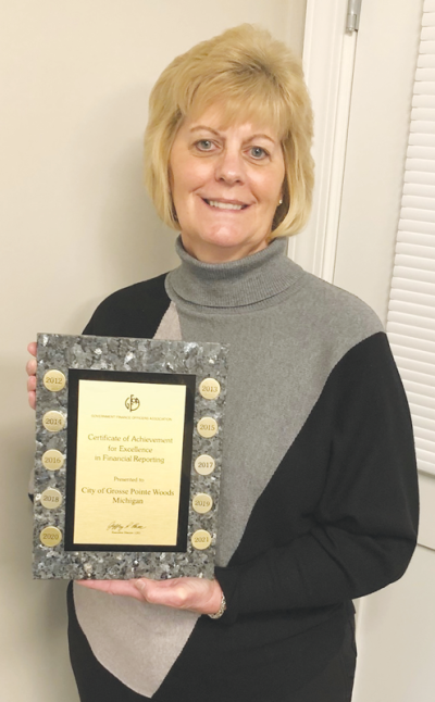  Grosse Pointe Woods Treasurer/Comptroller Shawn Murphy, in her office at Woods City Hall, holds a plaque that includes some of the city’s awards for its detailed audit reports. 