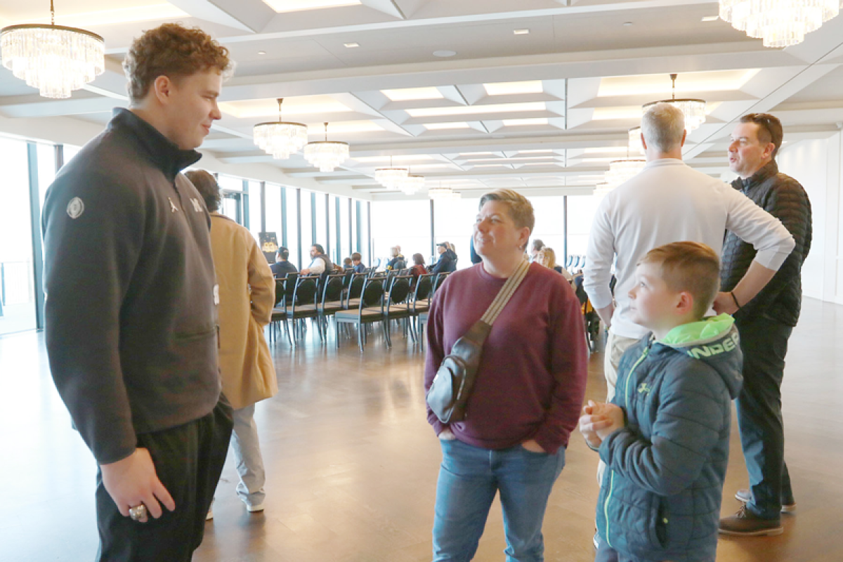  University of Michigan sophomore defensive lineman Joey Klunder spoke at a meet-and-greet held for the national champion Feb. 10 at The War Memorial in Grosse Pointe Farms.  ABOVE: Klunder, left, speaks with Grosse Pointe Woods resident Lisa Jaeger and her son, Andrew Jaeger-Karalla, during the meet-and-greet.  