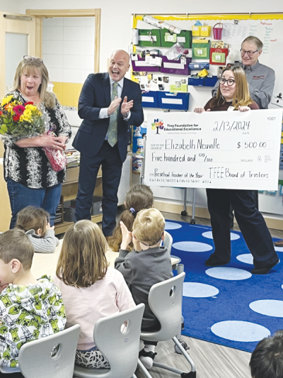  Elizabeth Neuville, an early childhood educator at the Troy School District Preschool, left, receives flowers and a check after being named the district’s Preschool Teacher of the Year. 