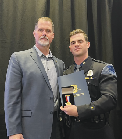 Michigan State Police trooper Maxwell Prince, right, receives the Medal of Valor alongside his father, former MSP Detective Sgt. Bill Prince, after trooper Prince was wounded in the line of duty last March. 