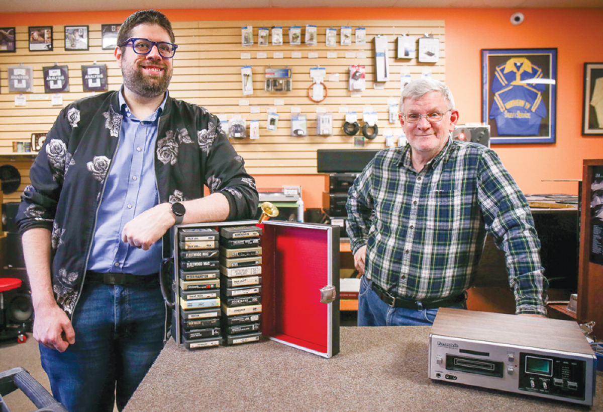  Madison Heights Mayor Pro Tem Mark Bliss, left, shares a small sample of his eight-track collection while visiting Northern Audio Service on March 26. With him is Mike Sheppard, the store’s president, showcasing an eight-track player. The business specializes in antique audio repair.   