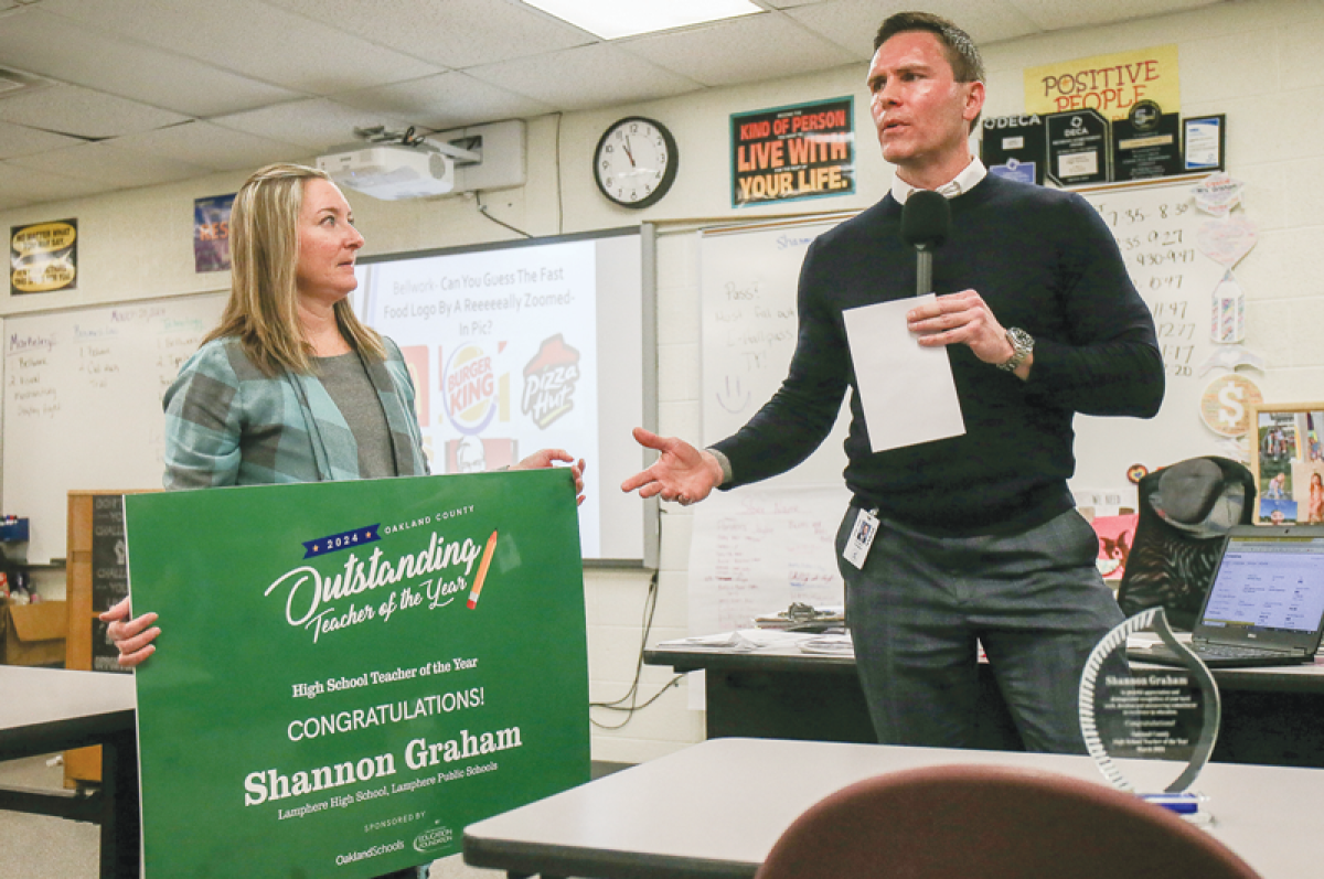  Rodney Thomas, the principal at Lamphere High, right, was among the school officials that surprised Shannon Graham, left, with the Oakland County Outstanding High School Teacher of the Year Award in her classroom March 20. Graham’s family — husband Nicholas and daughter Callista, 7 — were also present, bringing flowers and a balloon. 