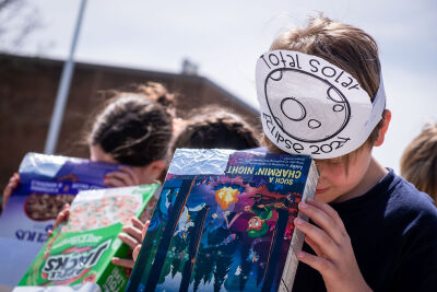  Village Oaks Elementary fourth-grader Michael Tuomi uses a pinhole viewer made out of a cereal box to safely watch the solar eclipse Monday, April 8, 2024, in Novi. 