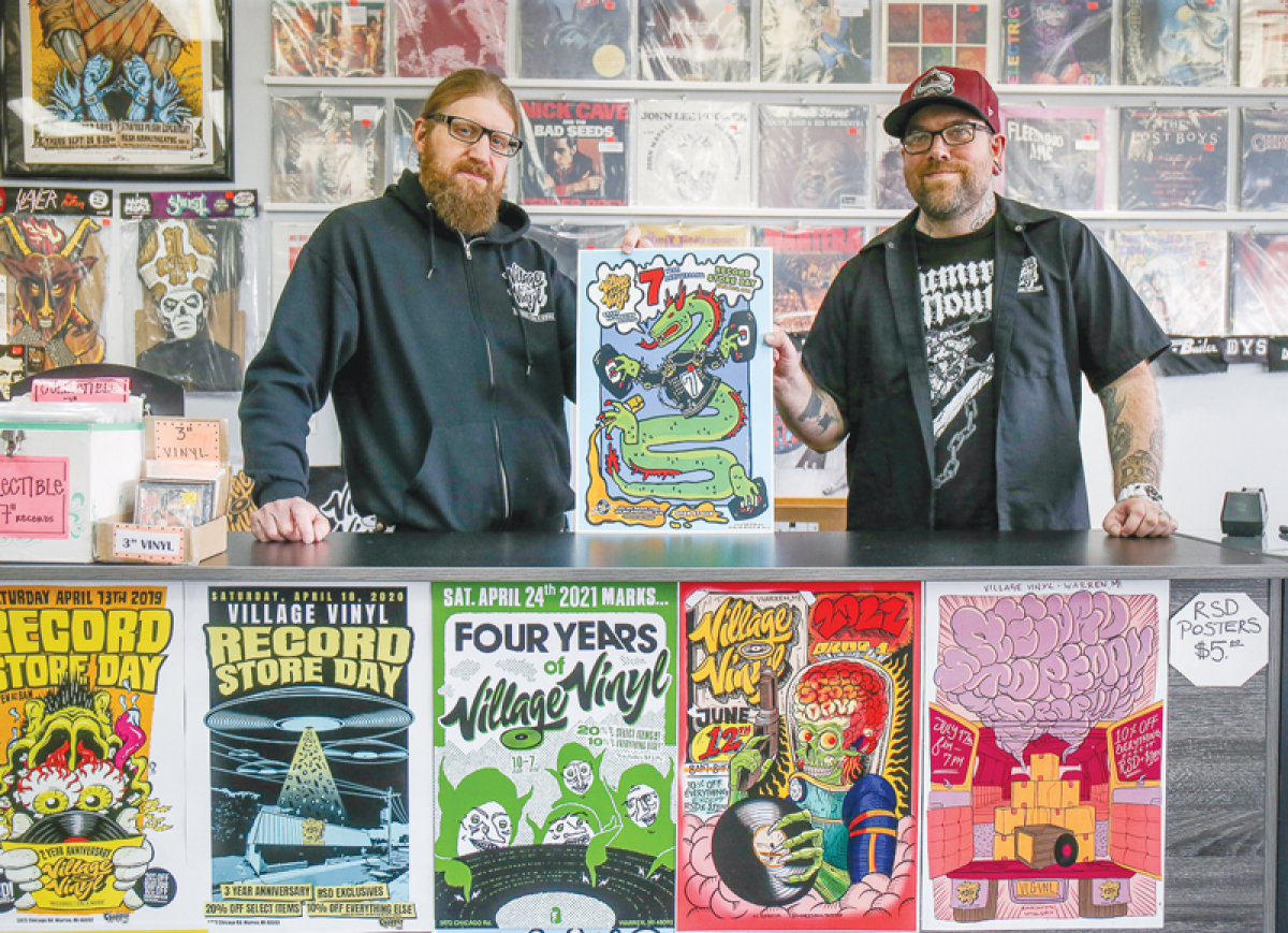  Village Vinyl owner John Lehl, left, and manager Adam Davey will be on hand to welcome customers on Record Store Day April 20. Pictured with them are posters from past Record Store Day events. 