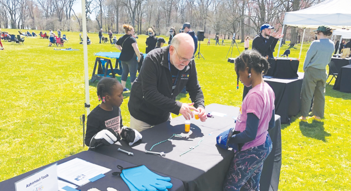  After getting instructions from Michigan Science Center educator Dennis Moylan, sisters Aissata-Lujean Kande, 6, and Emi-Dienaba Kande, 9, of Auburn Hills, put on heavy gloves and try to complete a series of timed fine dexterity tasks, such as opening a pill bottle, to replicate the challenges faced by space-suited astronauts April 8 at the Edsel and Eleanor Ford House in Grosse Pointe Shores. 