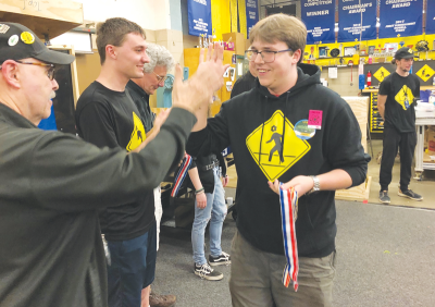  Gearheads team captain Drew Behringer — who’s graduating in June from Grosse Pointe North High School — high-fives one of the adult mentors as he and his teammates get their medals May 2. 