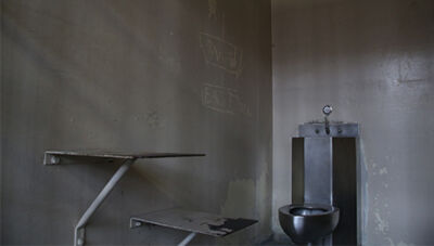  A cell at the Macomb County Jail’s maximum security block features a small table, a combined toilet-sink unit and the artwork of prior inmates carved into the wall. 