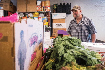  Jim Latour, a volunteer, walks through different food available during a food distribution event Tuesday, Aug. 16, 2022, at Harvest Time Christan Fellowship in Warren.  