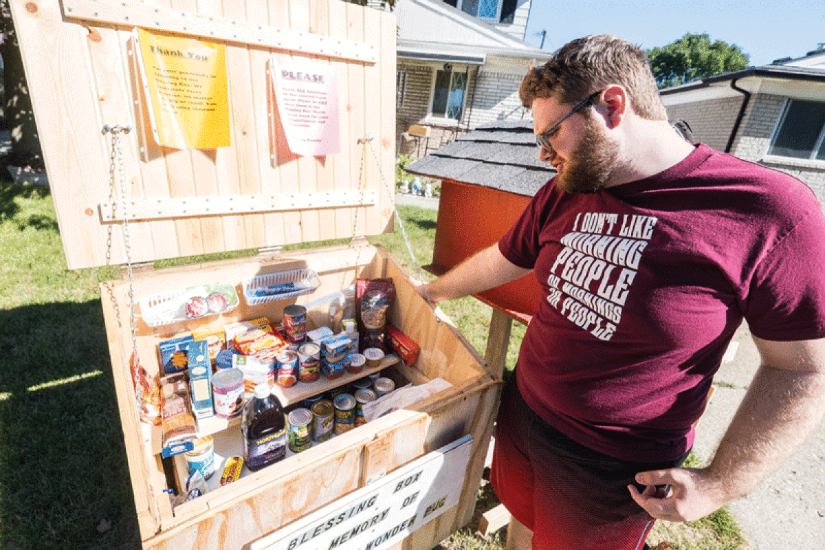  Dylan Soucy, 17, looks over items in the “blessings box” food pantry he constructed in the front yard of his Coolidge Avenue home Aug. 12. 