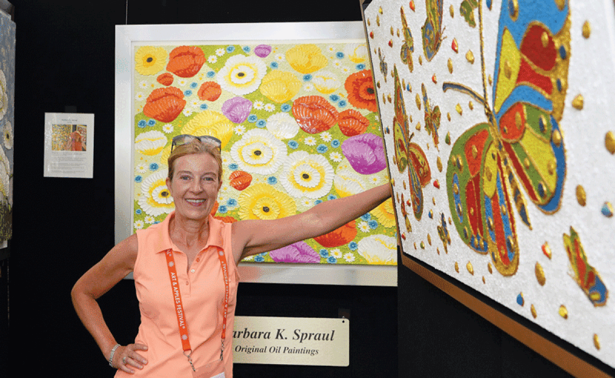  Artist Barbara Spraul stands near her oil paintings during last year’s Art and Apples Festival.  