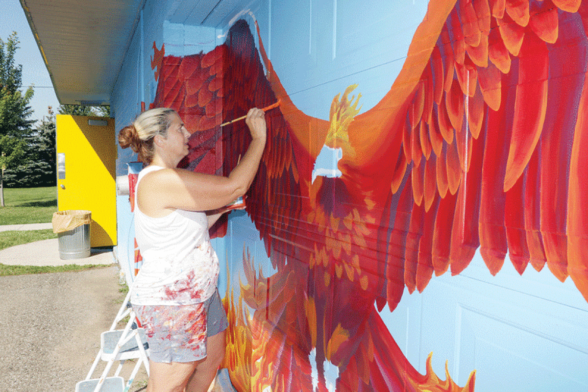  Jennifer Ramirez, of Madison Heights, paints a phoenix onto the wall of the shelter building at Huffman Park Aug. 28. 