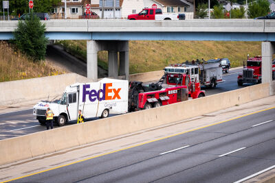 A heavy-duty wrecker prepares to remove a demolished delivery truck from the freeway. 