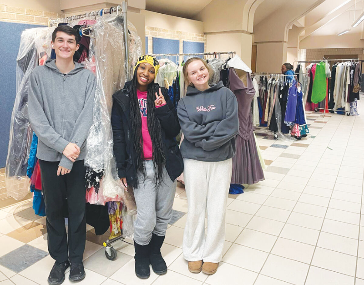  Nathan Wilson, the president of Lakeview High School’s Huskies with Heart, Carrington Barnes, a member of the Lake Shore High School Black Student Union, and Isabella Rexroad, Huskies with Heart secretary, stand in front of racks of dresses. 