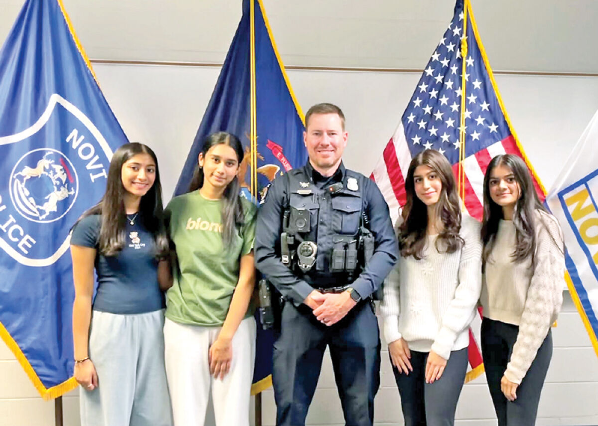  Novi High School students working to combat distracted driving pose for a picture with officer Adam McGee, of the Novi Police Department, after speaking with him on the issues he sees with distracted driving on the road. 