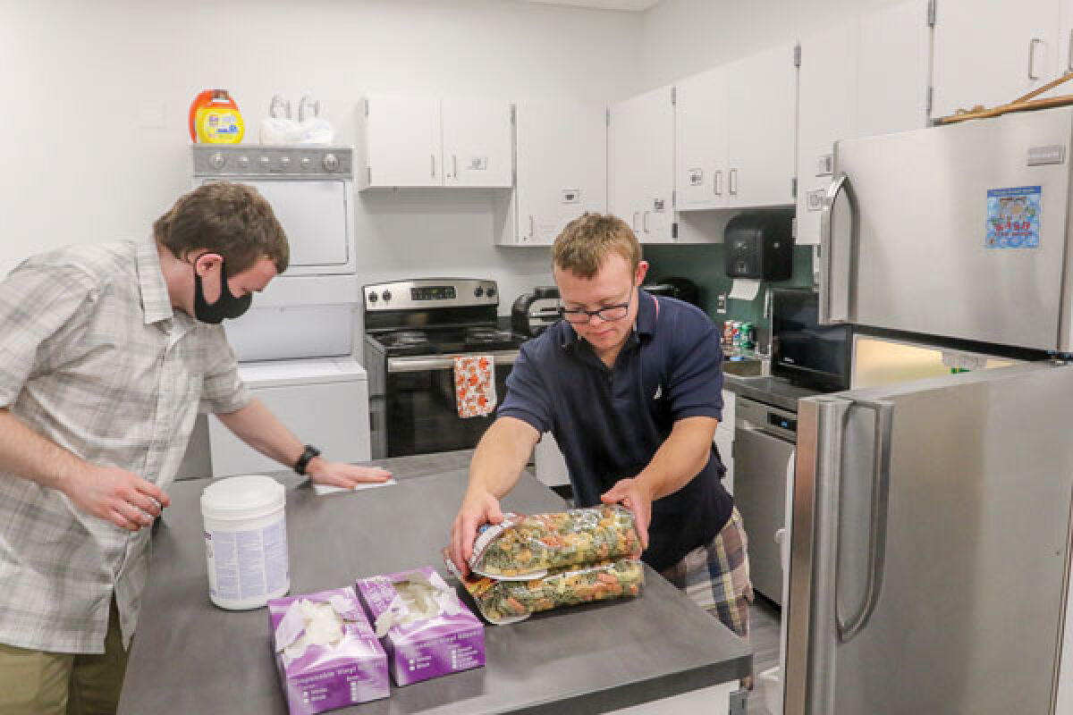  Jason Nunez, left, and Robby Heil, right, go through a daily routine in the apartment classroom at the Novi Adult Transition Center, which is housed at the ROAR Center. The classroom allows students ages 18-26 who have special needs to learn basic home economics skills. 