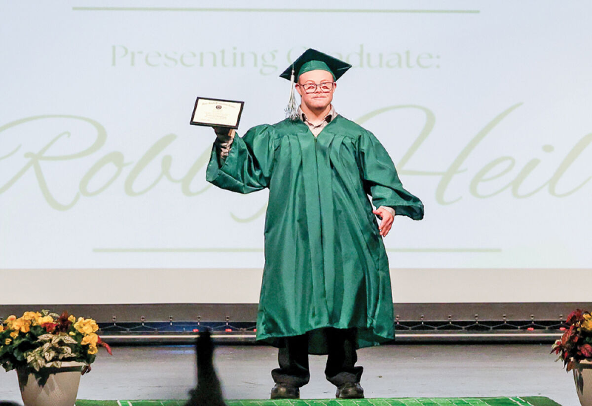  Robby Heil holds up his certificate of completion following his graduation from the Novi Adult Transition Center program on June 2. 