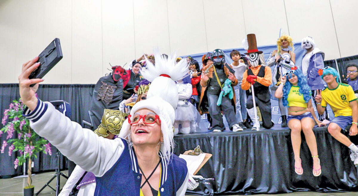  Disfusional Cosplay, known as Dis to friends, who served as master of ceremonies and judge during the cosplay contests at the MIAnime Convention in Novi, takes a selfie with the teen cosplay contest participants on Aug. 2. 