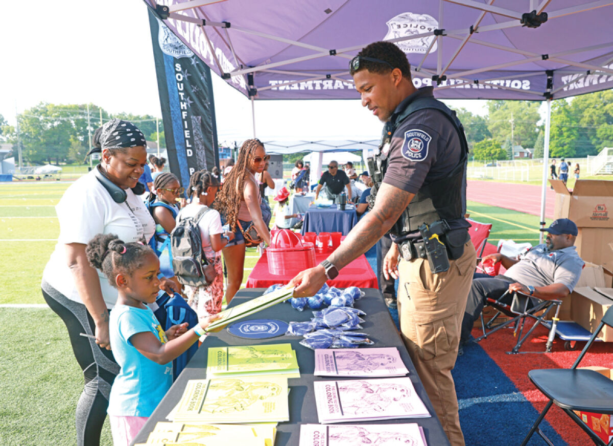  Southfield police officer Raymond Hood passes out coloring books Aug. 14 at the Southfield Public Schools Back to School Fair at Southfield High School for the Arts & Technology on Lahser Road. 