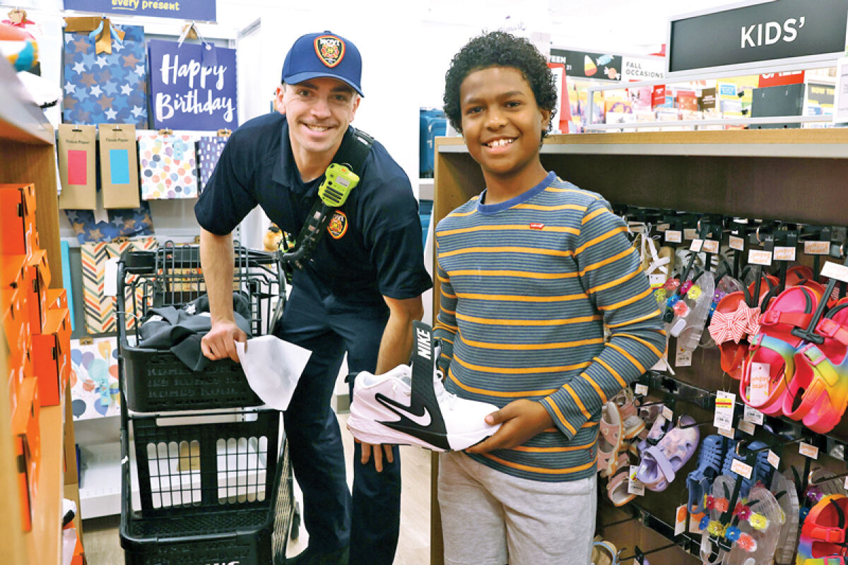  Novi firefighter/paramedic Anthony Giannini poses for a picture with Roland Alexander, 11, as they shop for back-to-school clothes Aug. 9 at Kohl’s. 