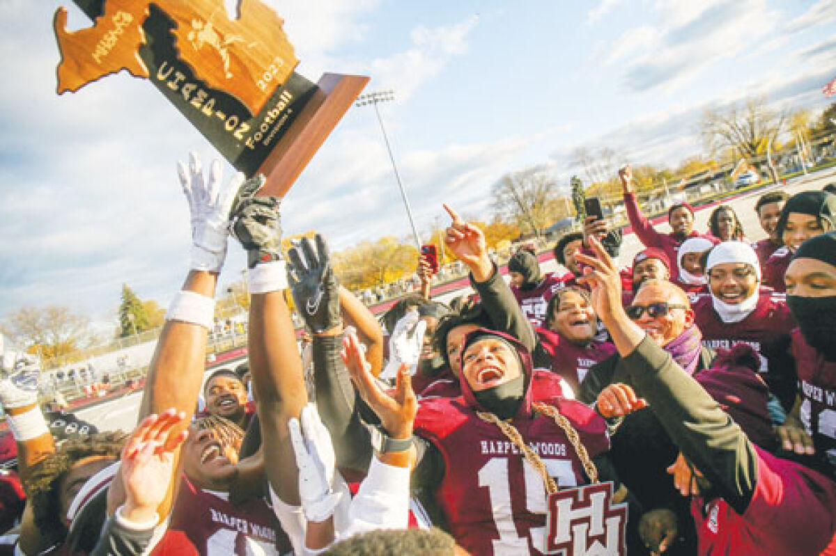  The Harper Woods football team celebrates after a win in 2023 with the MHSAA Division 4 trophy. 