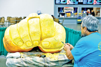  Johnnie Martinez, of Birch Run, carves a fist out of a 661-pound pumpkin to show “Detroit Grit.” 