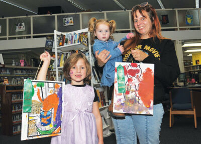  Zoey Brown, 7, and her sister Melody, 2,  show works they created for the Young Artist  Showcase at the Hazel Park District Library Sept. 6.  With them is their mother, Amanda.  