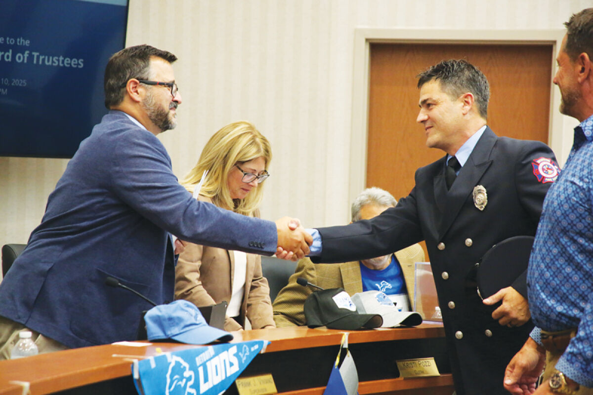  Macomb Township Supervisor Frank Viviano shakes hands with new full-time firefighter Thomas Smith after the township board meeting on Sept. 10. 