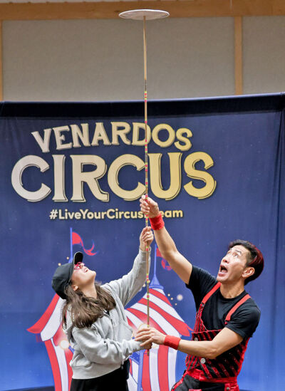  Preshow host Rob Lok performs a plate trick with Morgan G., a fourth grader in the Novi Community School District. 