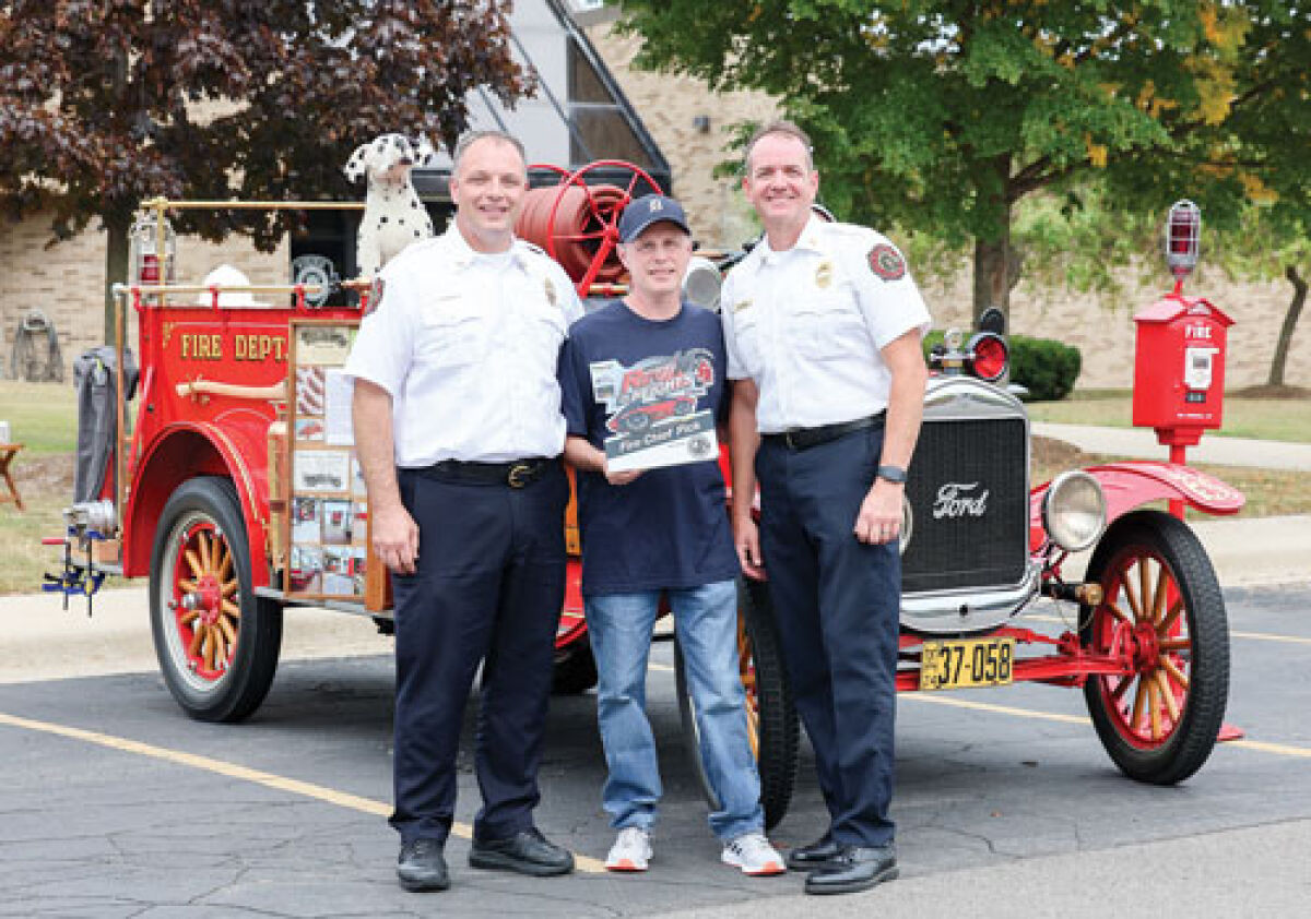  At the car show Revin’ in the Heights Sept. 13, Madison Heights Fire Chief Gregory Lelito, left, and Deputy Fire Chief Ray Gilson,  right, awarded the Fire Chief’s Pick trophy to a 1924 Prospect Fire Truck that Tim Toepel brought to the show.  Holding the award is Tim Burns, a city attorney for Madison Heights and one of the show’s sponsors.  