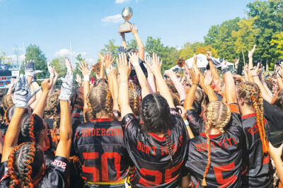  The Regina girls celebrate the school’s ninth straight powder-puff win over Marian with the game trophy.  