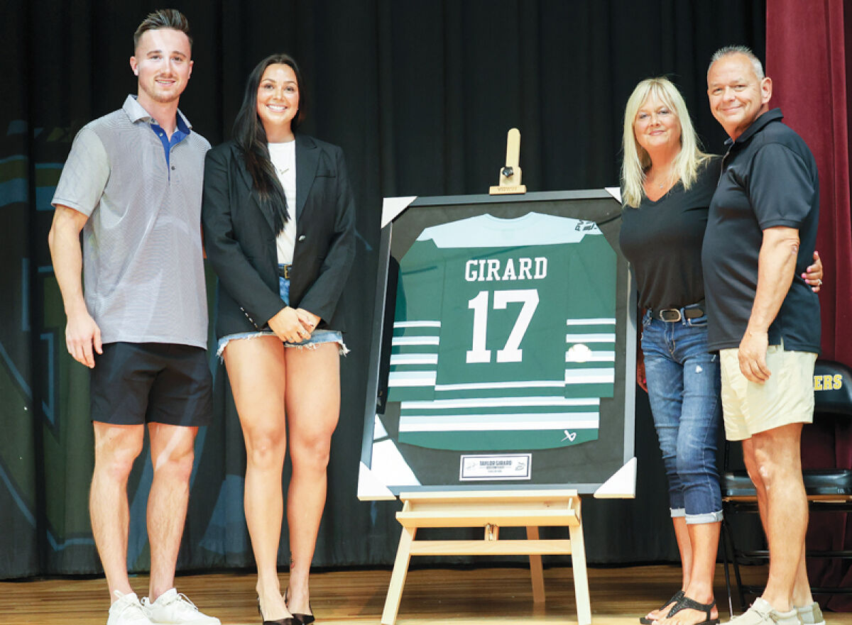  L’Anse Creuse North 2016 graduate Taylor Girard poses with her family next to her jersey that will be displayed in the school’s gymnasium. Girard is just the third athlete to be honored this way at LCN and is the first female. 