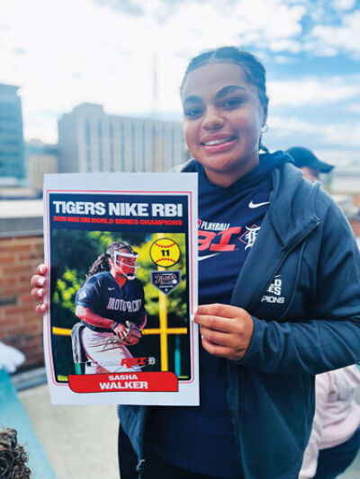 Sasha Walker poses with an enlarged trading card celebrating the team’s 2025 Nike RBI World Series Championship. 