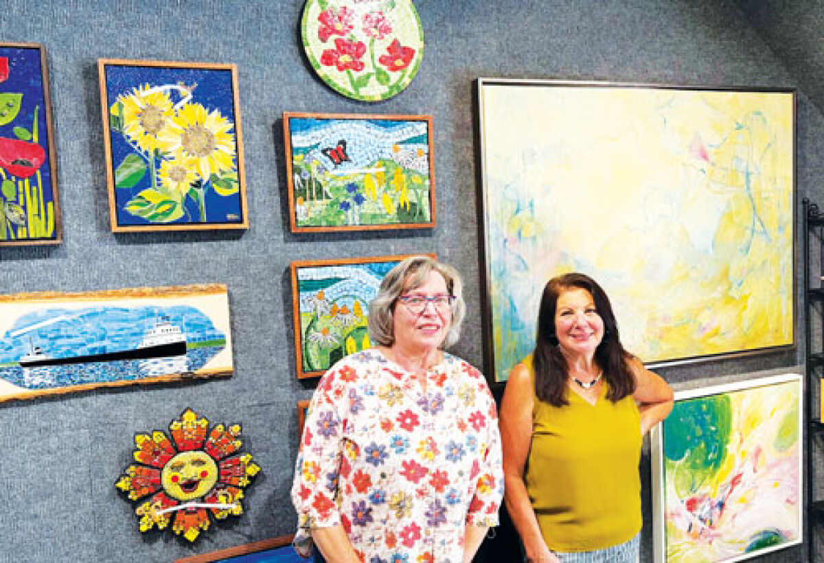  From left, artists Sue Majewski and Roselyn Palazzolo Rhodes stand in front of  some of their work on display now at Posterity in The Village. 
