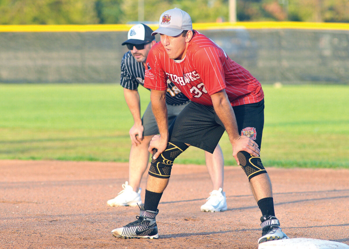  A Troy firefighter looks in from first base with a Troy police officer behind him in the field. 