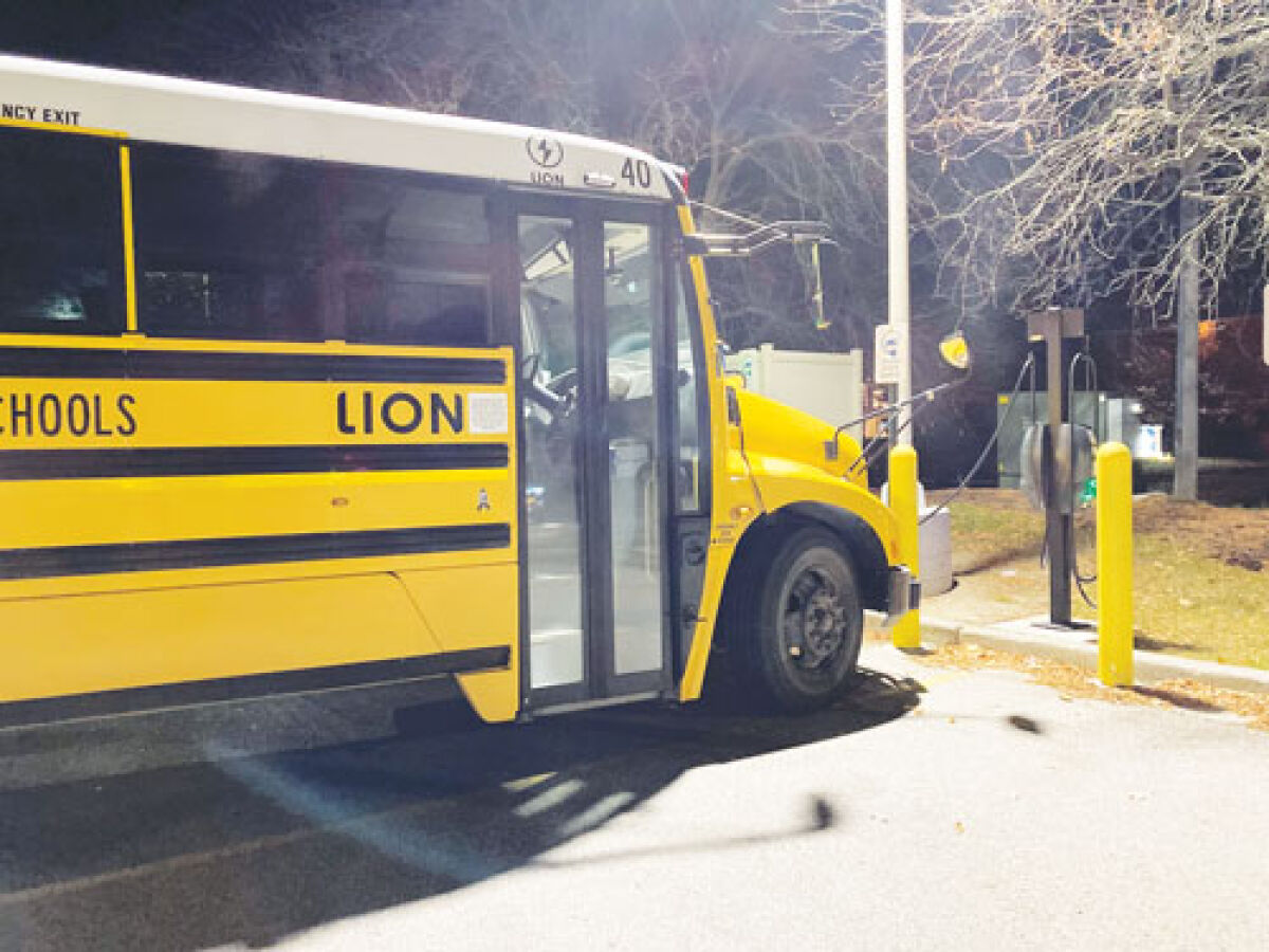 An electric school bus charges in a store parking lot. More than 20 schools and districts across Michigan have received state funding for new school buses — most of them electric — which will be built this winter.  