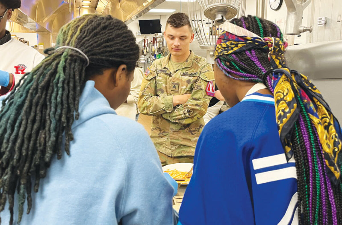 Army National Guard Sgt. Angel Weatherbee, center, checks out the meal ready to eat that Roseville High School culinary arts students Jordin Gayles, left, and Quintaysia Pope, both seniors, made from various ingredients 