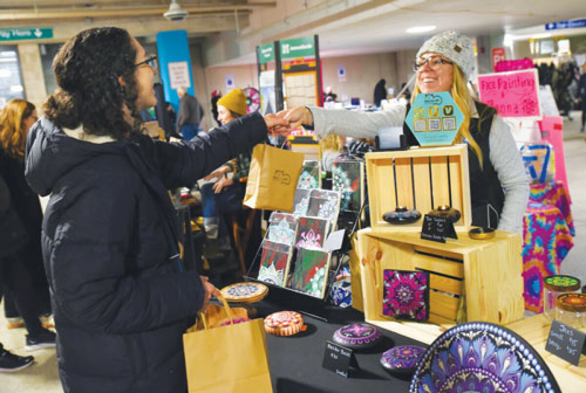  Kira Burnett, of Hazel Park, makes a purchase from artist Ashlee Beno at last year’s Ferndale  Underground Holiday Market. The third edition of the event will be held Nov. 15-16 on the  lower level of The dot parking structure. 