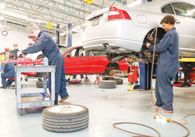  In class Nov. 19, senior Dylan Bush, left, looks for a tool while  senior David Nelson works on the brake system of a car.  