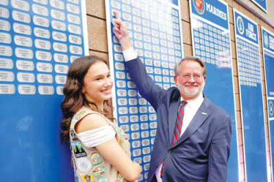  Audrey Henckel stands next to United State Sen. Gary Peters, an alumnus of Rochester High School,  as he points to his dad’s name, Herbert Peters, under “Army.” 
