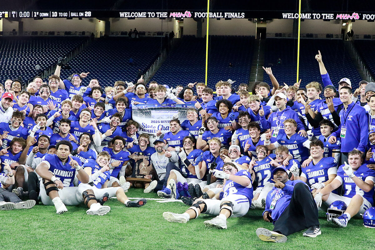  Players and coaches pose with the Michigan High School Athletic Association Division 1 state championship trophy after the team’s win. 